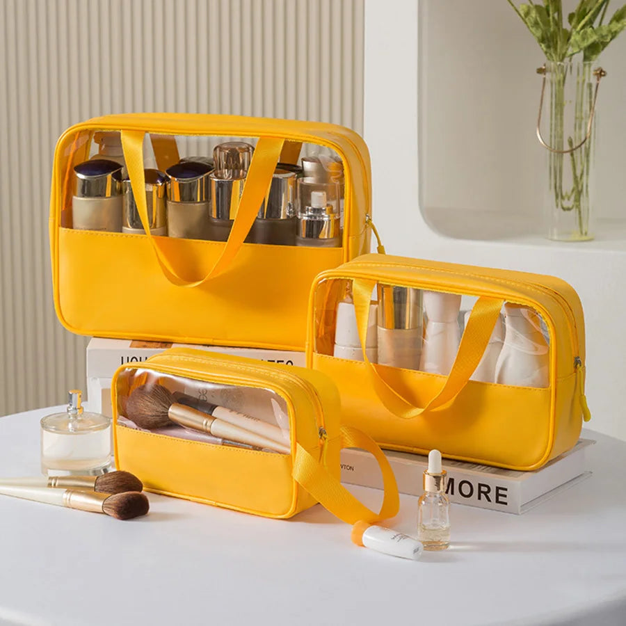 Set of three yellow matte translucent toiletry bags filled with skincare and makeup items, displayed on a vanity with books, brushes, and decor